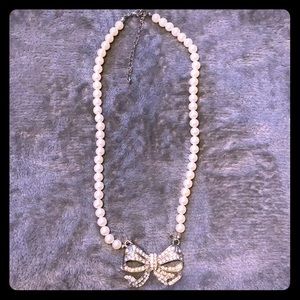 A pearl necklace with a silver bow & small stones